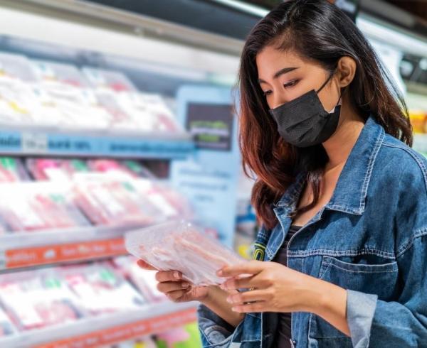 woman looking at meat in grocery store